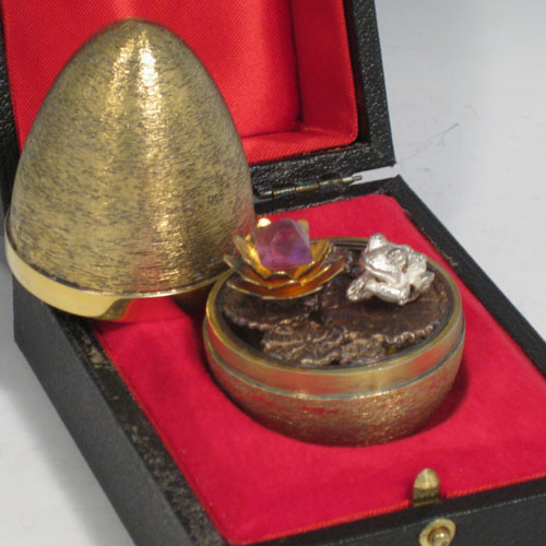 Sterling silver and gold-gilt surprise egg, made by Stuart Devlin of London in 1972. Having inside a frog sitting on lilly pads, together with an amethyst set lilly flower with leaves, all in its original satin and velvet-lined presentation box. This has the style number 28. Height 7.5 cms (3 inches). Total weight approx. 107g (3.5 troy ounces).