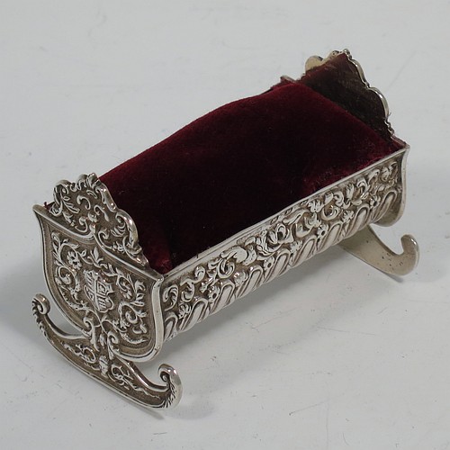 An Antique Victorian Sterling Silver pin cushion, in the form of a babies rocking crib, with hand-chased floral and fluted decoration, together with a maroon velvet covered cushion. Made by Saunders and Shepherd of Birmingham in 1896. The dimensions of this fine hand-made antique silver pin cushion are length 6 cms (2.3 inches), width 3.5 cms (1.3 inches), height 4 cms (1.5 inches), and it weighs approx. 33g (1 troy ounces).   