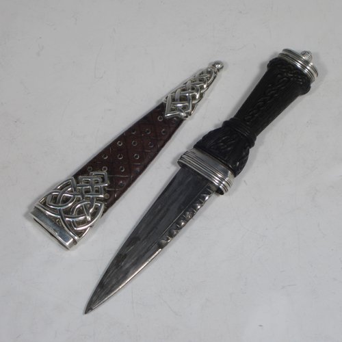 A Scottish Antique Victorian Sterling Silver Sgian Dubh ceremonial knife and scabbard, having a hand-made leather scabbard with Cymric style silver mounts, a black hand-carved Bog-Oak handle with finial and matching decoration, and an original steel blade. Made by James Ross of Edinburgh in 1888. The dimensions of this fine hand-made silver Sgian Dubh are length 23 cms (9 inches), and width 3 cms (1.25 inches).