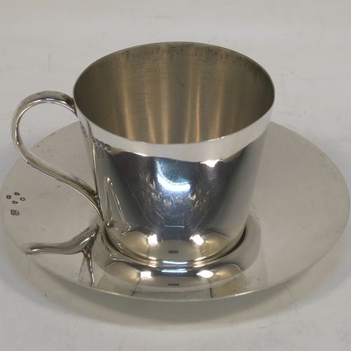 A very handsome Antique Victorian Sterling Silver Arts and Crafts style single tea cup and saucer, the cup having a very plain round body with tapering sides and a scroll handle, and the saucer having a matching plain round body. This elegant silver tea cup and saucer were made by Heath and Middleton of London in 1889. The dimensions of this fine antique silver tea cup and saucer are height 5 cms (2 inches), diameter of saucer 10 cms (4 inches), and with a total weight of approx. 94g (3 troy ounces).