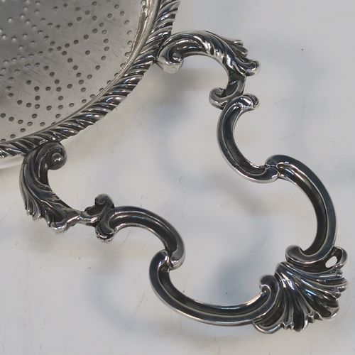 A very handsome Antique Georgian Sterling Silver lemon strainer, having a round hand-pierced main bowl body with an applied rope-twist border, and two cast scroll side-handles with shell terminals. This beautiful and original Georgian silver lemon strainer was made by Charles Aldridge and Henry Green of London in 1772. The dimensions of this fine hand-made antique silver lemon strainer are length 25,5 cms (10 inches), diameter of bowl 11 cms (4.25 inches), and it weighs approx. 117g (3.8 troy ounces).