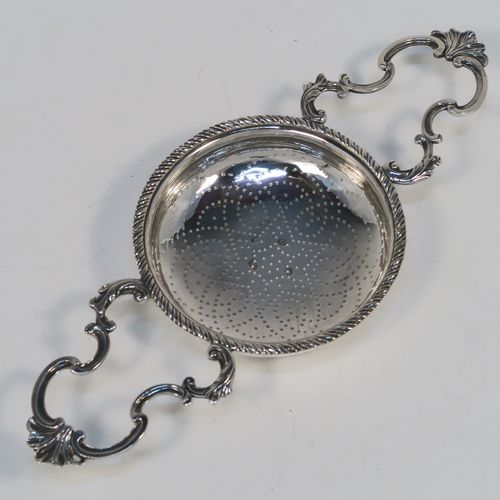 A very handsome Antique Georgian Sterling Silver lemon strainer, having a round hand-pierced main bowl body with an applied rope-twist border, and two cast scroll side-handles with shell terminals. This beautiful and original Georgian silver lemon strainer was made by Charles Aldridge and Henry Green of London in 1772. The dimensions of this fine hand-made antique silver lemon strainer are length 25,5 cms (10 inches), diameter of bowl 11 cms (4.25 inches), and it weighs approx. 117g (3.8 troy ounces).