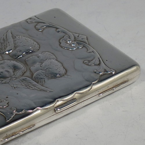 An Antique Victorian Sterling Silver Aide de Memoire and calling card case, having a rectangular body with hand-chased winged cherubs and floral decoration, hinged on one side and with a clasp on the other, and lined with light brown leather pockets. Made by William Comyns of London in 1898. The dimensions of this fine hand-made antique silver Aide de Memoire card case are length 10 cms (4 inches), width 7.5 cms (3 inches), and it weighs approx. 120g (3.9 troy ounces).    