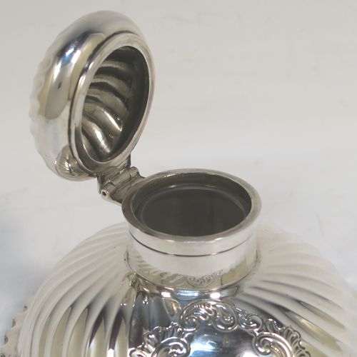 A very pretty Antique Victorian Sterling Silver desk set consisting of an inkstand and a pair of candle holders, in a round style with hand-chased swirl fluting and wavy-edge borders, the inkstand with a hinged lid and glass liner, the candlesticks with removable nozzles. This beautiful silver desk set was made by the Dixon Brothers of Sheffield in 1889. The dimensions of this fine antique silver desk set are height of candlesticks 14 cms (5.5 inches), and diameter of inkstand at base 11.5 cms (4.5 inches).  