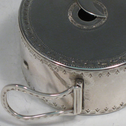 Antique Georgian sterling silver bougie-box, having a cylindrical body with bright-cut engraved bands of decoration, a flat invisibly hinged lid, an attached sickle moon-shaped wax trimmer, and a hinged buckle style loop handle. Made by Thomas Phipps and Edward Robinson II of London in 1785. Please note that the hallmark also includes a rare incuse duty mark (George III looking left), which was only in use for 18 months (between 1st December 1784 and 29th May, 1786). The dimensions of this fine hand-made silver bougie-box are diameter 5 cms (2 inches), height 2.5 cms (1 inch), and it weighs approx. 53g (1.7 troy ounces). 