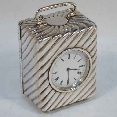 A very pretty Antique Victorian Sterling Silver carriage clock, having a rectangular upright body with hand-chased swirl-fluted decoration, with a hinged back door opening to the original clock movement mechanism and winder, a hinged and scrolled top carrying handle, and all sitting on four cushion feet. Made by Louis Augustus Leins of London in 1897. The dimensions of this fine hand-made antique silver carriage clock are height 7.5 cms (3 inches), width 5.5 cms (2.25 inches), and depth 4.5 cms (1.75 inches). Please note that this clock has been serviced and works properly.   