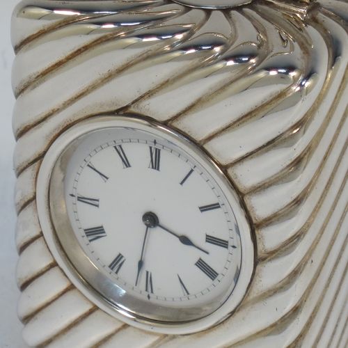 A very pretty Antique Victorian Sterling Silver carriage clock, having a rectangular upright body with hand-chased swirl-fluted decoration, with a hinged back door opening to the original clock movement mechanism and winder, a hinged and scrolled top carrying handle, and all sitting on four cushion feet. Made by Louis Augustus Leins of London in 1897. The dimensions of this fine hand-made antique silver carriage clock are height 7.5 cms (3 inches), width 5.5 cms (2.25 inches), and depth 4.5 cms (1.75 inches). Please note that this clock has been serviced and works properly.   