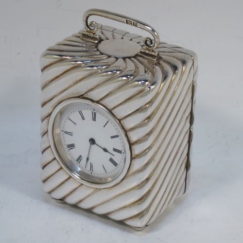 A very pretty Antique Victorian Sterling Silver carriage clock, having a rectangular upright body with hand-chased swirl-fluted decoration, with a hinged back door opening to the original clock movement mechanism and winder, a hinged and scrolled top carrying handle, and all sitting on four cushion feet. Made by Louis Augustus Leins of London in 1897. The dimensions of this fine hand-made antique silver carriage clock are height 7.5 cms (3 inches), width 5.5 cms (2.25 inches), and depth 4.5 cms (1.75 inches). Please note that this clock has been serviced and works properly.   