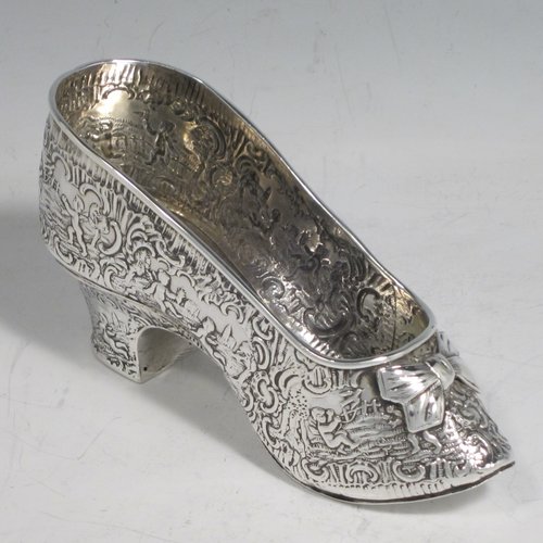 Antique Victorian sterling silver shoe, having a hand-chased body with floral decoration and scenes of winged cherubs, with a heal chased in the same style, and an applied front bow. Possibly Dutch in origin and imported into London in 1896 with full assay hallmarks. The dimensions of this fine hand-made silver shoe are height 7 cms (2.75 inches), length 14 cms (5.5 inches), width 4.5 cms (1.75 inches), and it weighs approx. 117g (3.8 troy ounces).   