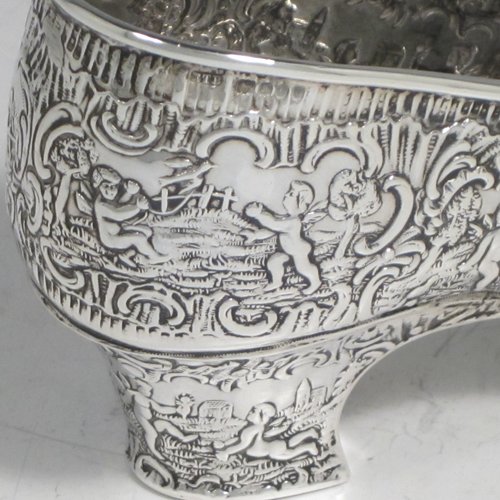 Antique Victorian sterling silver shoe, having a hand-chased body with floral decoration and scenes of winged cherubs, with a heal chased in the same style, and an applied front bow. Possibly Dutch in origin and imported into London in 1896 with full assay hallmarks. The dimensions of this fine hand-made silver shoe are height 7 cms (2.75 inches), length 14 cms (5.5 inches), width 4.5 cms (1.75 inches), and it weighs approx. 117g (3.8 troy ounces).   