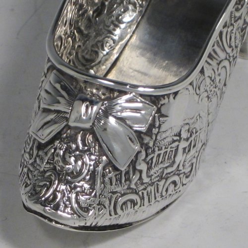 Antique Victorian sterling silver shoe, having a hand-chased body with floral decoration and scenes of winged cherubs, with a heal chased in the same style, and an applied front bow. Possibly Dutch in origin and imported into London in 1896 with full assay hallmarks. The dimensions of this fine hand-made silver shoe are height 7 cms (2.75 inches), length 14 cms (5.5 inches), width 4.5 cms (1.75 inches), and it weighs approx. 117g (3.8 troy ounces).   