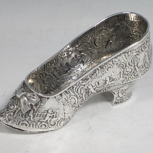 Antique Victorian sterling silver shoe, having a hand-chased body with floral decoration and scenes of winged cherubs, with a heal chased in the same style, and an applied front bow. Possibly Dutch in origin and imported into London in 1896 with full assay hallmarks. The dimensions of this fine hand-made silver shoe are height 7 cms (2.75 inches), length 14 cms (5.5 inches), width 4.5 cms (1.75 inches), and it weighs approx. 117g (3.8 troy ounces).   