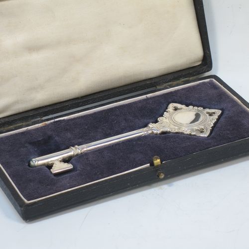 A handsome Sterling Silver 21st key to life, having a cast body with a hand-chased Gothic style handle, a plain shank, hand-chased collars, and a plain key bit, all in its original cream satin and dark-blue velvet-lined presentation box. Made by Vaughton and Sons of Birmingham in 1932. The dimensions of this fine hand-made silver 21st key to life are length 11 cms (4.3 inches) and it weighs approx. 43g (1.4 troy ounces).  