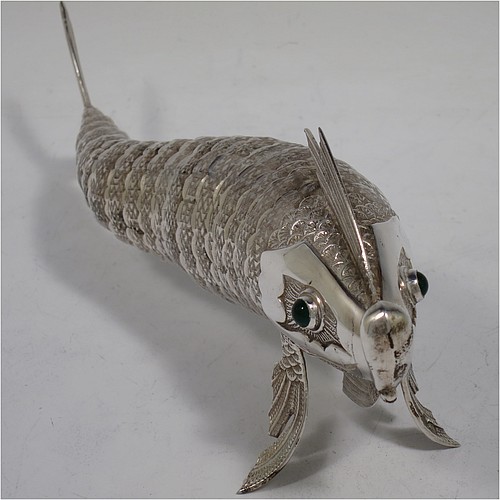 A very pretty Antique Edwardian Silver Articulated fish, having hand-chased scales and fins, and with two green cabochon glass eyes. Made in Spain in ca. 1900. On one of the lower fins you can see the hallmark of a Pentagram that is a Spanish quality mark indicating a minimum of 915 Silver purity (Sterling Standard is 925). The dimensions of this fine hand-made antique Articulated Silver fish are length 20 cms (8 inches), height 7.5 cms (3 inches), and it weighs approx. 138g (4.4 troy ounces).