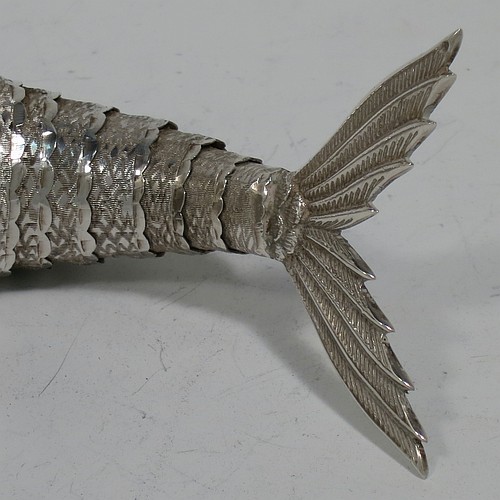 A very pretty Antique Edwardian Silver Articulated fish, having hand-chased scales and fins, and with two green cabochon glass eyes. Made in Spain in ca. 1900. On one of the lower fins you can see the hallmark of a Pentagram that is a Spanish quality mark indicating a minimum of 915 Silver purity (Sterling Standard is 925). The dimensions of this fine hand-made antique Articulated Silver fish are length 20 cms (8 inches), height 7.5 cms (3 inches), and it weighs approx. 138g (4.4 troy ounces).