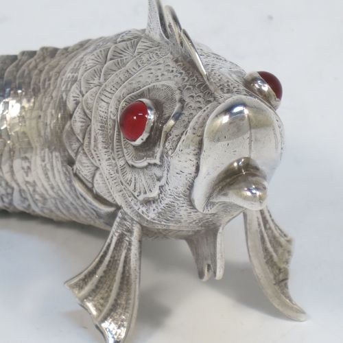 A very pretty Antique Edwardian Silver Articulated fish, having hand-chased scales and fins, and with two red glass eyes (possibly garnets). Made in Spain in ca. 1900. On one of the lower fins you can see the hallmark of a Pentagram that is a Spanish quality mark indicating a minimum of 915 Silver purity (Sterling Standard is 925). The dimensions of this fine hand-made antique Articulated Silver fish are length 17 cms (6.75 inches), height 5.5 cms (2.25 inches), and it weighs approx. 92g (3 troy ounces).   