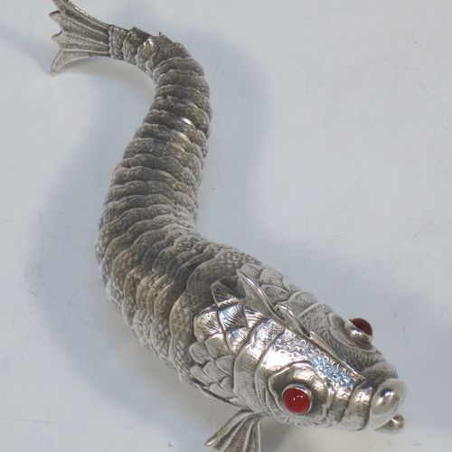 A very pretty Antique Edwardian Silver Articulated fish, having hand-chased scales and fins, and with two red glass eyes (possibly garnets). Made in Spain in ca. 1900. On one of the lower fins you can see the hallmark of a Pentagram that is a Spanish quality mark indicating a minimum of 915 Silver purity (Sterling Standard is 925). The dimensions of this fine hand-made antique Articulated Silver fish are length 17 cms (6.75 inches), height 5.5 cms (2.25 inches), and it weighs approx. 92g (3 troy ounces).   