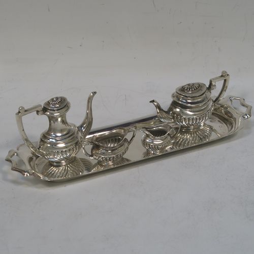 An elegant Sterling Silver miniature tea and coffee service in a Queen Anne half-fluted style, consisting of a coffee pot, tea pot, sugar bowl, milk jug, and a two-handled tray. All made by D. J. Silver Ltd., of London in 1973 (the tray for 1969). The dimensions of this fine hand-made silver miniature tea and coffee set are are height 4 cms (1.5inches), length 14.5 cms (5.75 inches), width 4 cms (1.5 inches), and it weighs approx. 67g (2.2 troy ounces).   