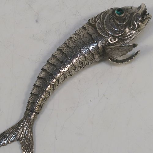 A very pretty Antique Edwardian Silver Articulated fish, having hand-chased scales and fins, and with two green glass eyes. This beautiful articulated silver fish model was made in Cordoba, Spain in ca. 1940. On one of the lower fins you can see the hallmark of a Pentagram that is a Spanish quality mark indicating a minimum of 915 Silver purity (Sterling Standard is 925), and in a separate mark the letters CO representing Cordoba. The dimensions of this fine hand-made antique Articulated Silver fish are length 15 cms (6 inches), height 4 cms (1.5 inches), and it weighs approx. 72g (2.3 troy ounces).   