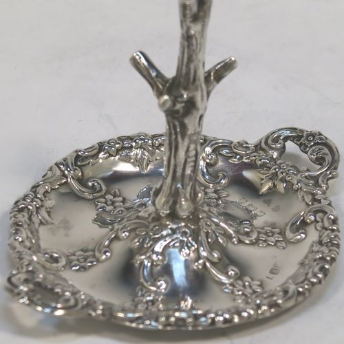 A very pretty Antique Victorian Sterling Silver ring tree, having a central naturalistic tree for rings sitting on a round base with two side-handles, with hand-chased floral and scroll decoration. This beautiful silver ring tree and base was made by Henry Matthews of Birmingham in 1900. The dimensions of this fine hand-made antique silver tree ring are height 7.5 cms (3 inches), diameter 8 cms (3 inches), and it weighs approx. 36g (1.2 troy ounce).   