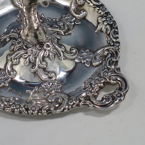 A very pretty Antique Victorian Sterling Silver ring tree, having a central naturalistic tree for rings sitting on a round base with two side-handles, with hand-chased floral and scroll decoration. This beautiful silver ring tree and base was made by Henry Matthews of Birmingham in 1900. The dimensions of this fine hand-made antique silver tree ring are height 7.5 cms (3 inches), diameter 8 cms (3 inches), and it weighs approx. 36g (1.2 troy ounce).   