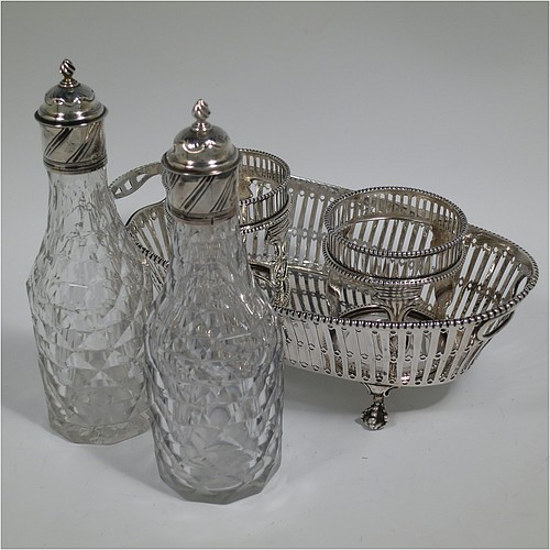 An Antique Georgian Sterling Silver oil and vinegar set, having an oval boat-shaped body with hand-pierced decoration and applied bead-edged borders, with cut-out loop side handles, a pair of hand-cut crystal bottles with stoppers in matching round galleried frames, and all sitting on four cast claw and ball feet. Made by Thomas Northcote of London in 1792. The dimensions of this fine hand-made antique silver oil and vinegar set are length 21.5 cms (8.5 inches), height (excl. bottles) 9 cms (3.5 inches), width 11.5 cms (4.5 inches), and with a total weight of approx. 400g (12.9 troy ounces). Please note that this item is crested. 