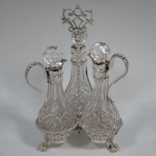 A very pretty Antique Victorian Sterling Silver oil and vinegar set, having three hand-cut crystal bottles with silver mounts, stoppers, and bead-edged scroll handles. All sitting in a hand-pierced frame with matching bead-work, a twisted central and hand-pierced handle, and all sitting on three cast claw and ball feet. Made by Martin Hall and Co., of Sheffield in 1857. The dimensions of this fine hand-made antique silver and crystal oil and vinegar set are height 19 cms (7.5 inches), width 11 cms (4.3 inches), and the frame  weighs approx. 170g (5.5 troy ounces).    