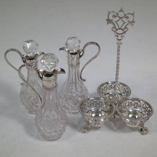 A very pretty Antique Victorian Sterling Silver oil and vinegar set, having three hand-cut crystal bottles with silver mounts, stoppers, and bead-edged scroll handles. All sitting in a hand-pierced frame with matching bead-work, a twisted central and hand-pierced handle, and all sitting on three cast claw and ball feet. Made by Martin Hall and Co., of Sheffield in 1857. The dimensions of this fine hand-made antique silver and crystal oil and vinegar set are height 19 cms (7.5 inches), width 11 cms (4.3 inches), and the frame  weighs approx. 170g (5.5 troy ounces).    