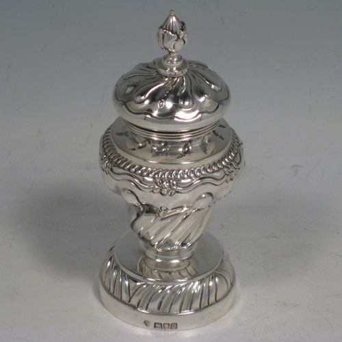 Antique Edwardian sterling silver pepper grinder, having a hand-chased body with floral decoration and swirl fluting, a cast floral finial, and sitting on a pedestal foot. Made in London in 1907. Height 12 cms (4.75 inches), diameter at base 5 cms (2 inches). Weight approx. 140g (4.5 troy ounces).