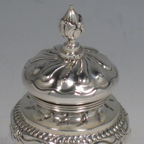 Antique Edwardian sterling silver pepper grinder, having a hand-chased body with floral decoration and swirl fluting, a cast floral finial, and sitting on a pedestal foot. Made in London in 1907. Height 12 cms (4.75 inches), diameter at base 5 cms (2 inches). Weight approx. 140g (4.5 troy ounces).