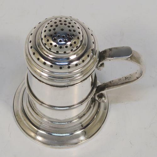 A very handsome Silver Kitchen pepper made in the Britannia Standard, having a plain round straight-sided body with an applied central girdle, a pull-off hand-pierced lid, a cast scroll side-handle, and siting on a stepped collet foot. This Britannia Standard silver kitchen pepper pot was made by the Pairpoint Brothers of London in 1929. The dimension of this silver kitchen pepper are height 7.5 cms (3 inches), length 7 cms (2.75 inches), and it weighs approx. 149g (4.8 troy ounce).   