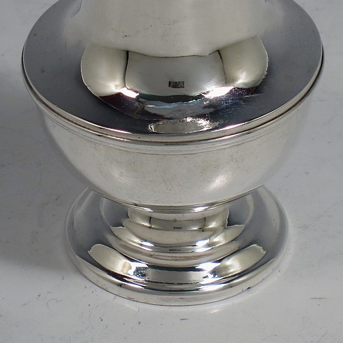 An Antique Victorian Sterling Silver pepper shaker or pot in a George II style, having a plain round bellied body, with reeded borders, pull-off hand-pierced lid with a cast finial, and sitting on a pedestal foot. Made by Nathan & Hayes of Chester in 1897. The dimensions of this fine hand-made antique silver pepper pot or shaker are height 11 cms (4.3 inches), diameter 5 cms (2 inches), and it weighs approx. 85g (2.7 troy ounces).