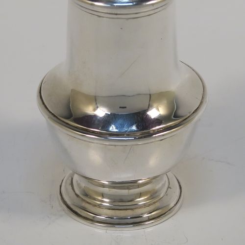 A very handsome Antique Sterling Silver pepper pot, in a Georgian style, having a plain round bellied body with applied reeded borders, a hand-pierced pull-off lid with urn-shaped finial, and sitting on a pedestal foot. This elegant silver pepper pot was made by Goldsmiths and Silversmiths of London in 1920. The dimensions of this fine hand-made antique silver pepper pot are height 11 cms (4.3 inches), diameter of main body 4.5 cms (1.75 inches), and it weighs approx. 105g (3.4 troy ounces).   