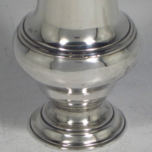 An Antique Georgian sterling silver pepper pot, having a plain round baluster body, a hand-pierced pull-off lid with flame finial, and sitting on a pedestal foot. Made by James Delmester of London in 1766. The dimensions of this fine hand-made antique silver pepper pot are height 12 cms (4.75 inches), diameter of main body 4.5 cms (1.75 inches), and it weighs approx. 63g (2 troy ounces).