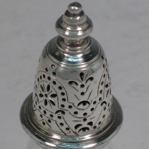    Sterling silver pair of pepper pots, in a George I style, having round plain bellied bodies with a central reeded band, pull-off hand-pierced lids with cast knop finials, and sitting on pedestal feet. Made in London in 1930/31. Height 11 cms (4.25 inches), diameter of bodies 4 cms (1.5 inches). Total weight 177g (5.7 troy ounces).