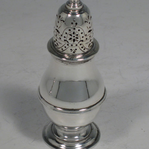    Sterling silver pair of pepper pots, in a George I style, having round plain bellied bodies with a central reeded band, pull-off hand-pierced lids with cast knop finials, and sitting on pedestal feet. Made in London in 1930/31. Height 11 cms (4.25 inches), diameter of bodies 4 cms (1.5 inches). Total weight 177g (5.7 troy ounces).