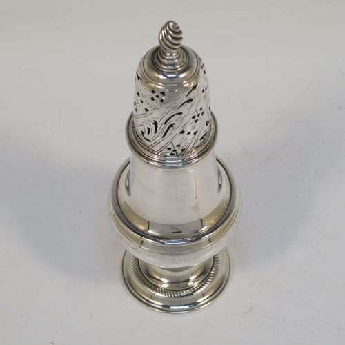 A handsome Antique Georgian Sterling Silver pepper pot, having a plain round bellied body, a hand-pierced pull-off lid with swirl finial, and sitting on a pedestal foot. This elegant antique silver pepper pot was made by John Delmester of London in 1764. The dimensions of this fine hand-made silver pepper pot are height 15 cms (6 inches), diameter of main body 5 cms (2 inches), and it weighs approx. 150g (4.8 troy ounces).   