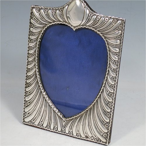 A very pretty Antique Victorian Sterling Silver photograph frame, having a heart-shaped aperture, surrounded by a hand-chased body with fluted decoration, and a wood-backed easel frame with brass fittings. Made by William Comyns of London in 1898. The internal dimensions of this fine hand-made antique silver photo frame are 12.5 cms (5 inches) high by 9.5 cms (3.75 inches) wide.   