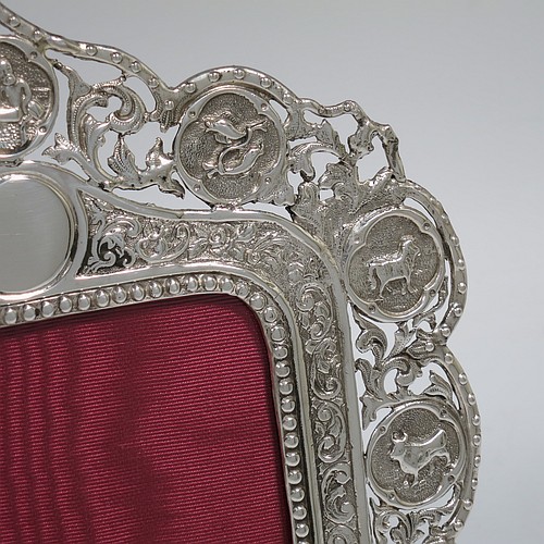 A very pretty and unusual Antique Victorian Sterling Silver photograph frame, having a rectangular aperture, surrounded by a bead and floral border with a lower heart-shaped cartouche and an upper round cartouche, all surrounded again by a hand-chased border with the twelve signs of the Zodiac, and a maroon velvet-backed easel frame. Made by Charles Boyton of London in 1888. The internal dimensions of this fine hand-made antique silver Zodiac sign photo frame are 9.5 cms (3.75 inches) wide by 7.5 cms (3 inches) high.    