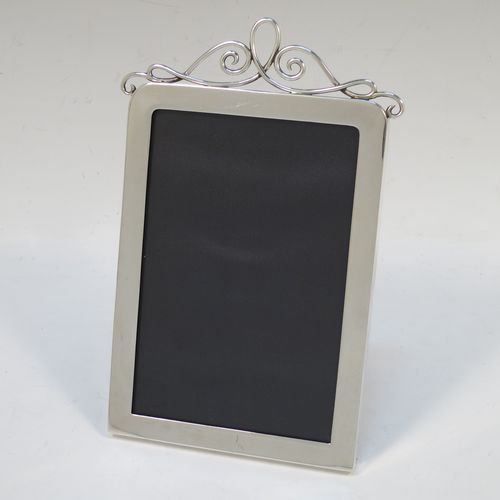 A handsome Antique Edwardian Sterling Silver portrait photograph frame, having a plain hand-made rectangular body with rounded top corners, a pretty applied wire-work top mount, and a maroon leather-backed easel frame. Made by J. Batson and Sons of London in 1902. The internal dimensions of this fine hand-made antique silver photo frame are height 13 cms (5.25 inches), and width 9 cms (3.5 inches).  