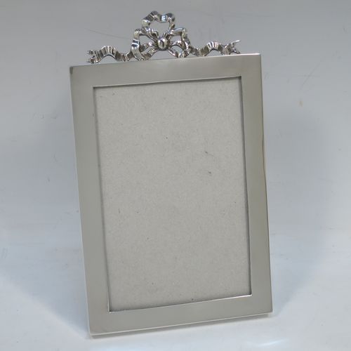 A very elegant Antique Edwardian Sterling Silver photograph frame, having a plain hand-made rectangular portrait body, an applied cast ribbon and bow top mount, and a black wood-backed easel frame. Made by the Asprey Brothers of London in 1902. The internal dimensions of this fine hand-made antique silver photo frame are height 13 cms (5 inches), by width 8.5 cms (3.3 inches).  