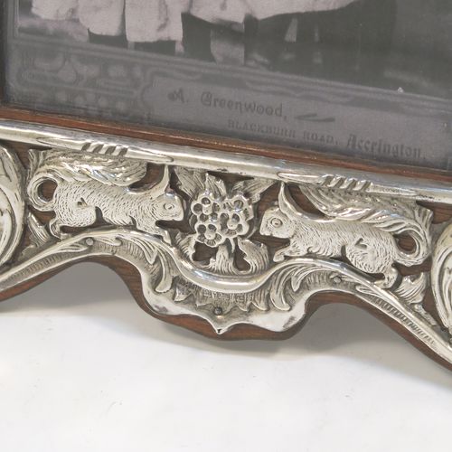 A very pretty Antique Edwardian Sterling Silver Art Nouveau style photograph frame, having a hand-chased and pinned body with flowers, birds, squirrels, and scroll decoration, a top central vacant cartouche, and wood backed easel frame. This beautiful Art Nouveau silver photo frame was made by Deakin and Francis of Birmingham in 1902. The internal dimensions of this fine hand-made antique silver photo frame are 14 cms (5.5 inches) high by 10 cms (4 inches) wide.  