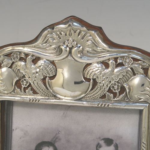 A very pretty Antique Edwardian Sterling Silver Art Nouveau style photograph frame, having a hand-chased and pinned body with flowers, birds, squirrels, and scroll decoration, a top central vacant cartouche, and wood backed easel frame. This beautiful Art Nouveau silver photo frame was made by Deakin and Francis of Birmingham in 1902. The internal dimensions of this fine hand-made antique silver photo frame are 14 cms (5.5 inches) high by 10 cms (4 inches) wide.  