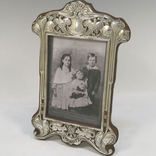 A very pretty Antique Edwardian Sterling Silver Art Nouveau style photograph frame, having a hand-chased and pinned body with flowers, birds, squirrels, and scroll decoration, a top central vacant cartouche, and wood backed easel frame. This beautiful Art Nouveau silver photo frame was made by Deakin and Francis of Birmingham in 1902. The internal dimensions of this fine hand-made antique silver photo frame are 14 cms (5.5 inches) high by 10 cms (4 inches) wide.  