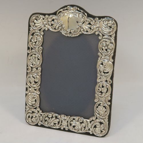 A very pretty Antique Victorian Sterling Silver photograph frame, having a hand-pierced border with  scroll-work and floral decoration, and all pinned to an original dark blue velvet-backed easel frame. This beautiful antique silver photo frame was made by Henry Matthews of Birmingham in 1901. The internal dimensions of this fine hand-made antique silver photo frame are 14 cms (5.5 inches) high by  10 cms (4 inches) wide.  