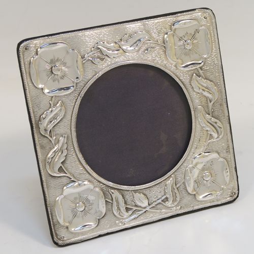 A very pretty Art Nouveau Antique Edwardian Sterling Silver photograph frame, having a round aperture with a glass cover, surrounded by rope-twist border and hand-chased floral poppy decoration, and all pinned to an original blue velvet-backed easel frame. This beautiful antique silver photo frame was made by A. and J. Zimmerman of Birmingham in 1905. The internal dimensions of this fine hand-made Art Nouveau antique silver photo frame are 8 cms (3 inches) in diameter.   