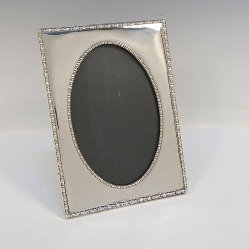 An elegant Antique Sterling Silver photograph frame, having an oval aperture, surrounded by pearl and bead borders, and all pinned to an original black stained wooden easel frame. This beautiful antique silver photo frame was made by the Deakin Brothers of Sheffield in 1916. The internal dimensions of this fine hand-made antique silver photo frame are height 19.5 cms (7.75 inches), and width 12 cms (4.75 inches).   