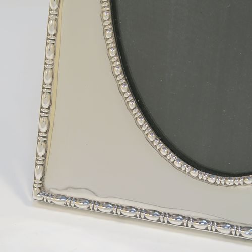 An elegant Antique Sterling Silver photograph frame, having an oval aperture, surrounded by pearl and bead borders, and all pinned to an original black stained wooden easel frame. This beautiful antique silver photo frame was made by the Deakin Brothers of Sheffield in 1916. The internal dimensions of this fine hand-made antique silver photo frame are height 19.5 cms (7.75 inches), and width 12 cms (4.75 inches).   