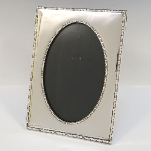 An elegant Antique Sterling Silver photograph frame, having an oval aperture, surrounded by pearl and bead borders, and all pinned to an original black stained wooden easel frame. This beautiful antique silver photo frame was made by the Deakin Brothers of Sheffield in 1916. The internal dimensions of this fine hand-made antique silver photo frame are height 19.5 cms (7.75 inches), and width 12 cms (4.75 inches).   