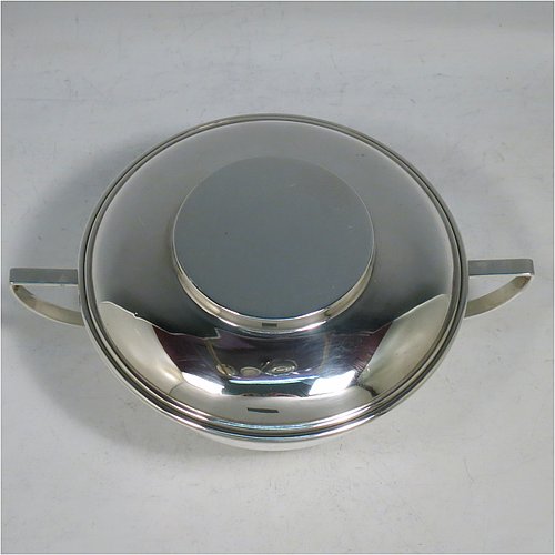 A Sterling Silver porringer and lid, having a plain round bellied body, with two scroll side handles, a pull-off cover, and all sitting on a collet foot. Made by George Unite of Birmingham in 1916. The dimensions of this fine hand-made silver porringer and lid are height 7 cms (2.75 inches), spread across arms 16.5 cms (6.5 inches), and it weighs approx. 218g (7 troy ounces).   